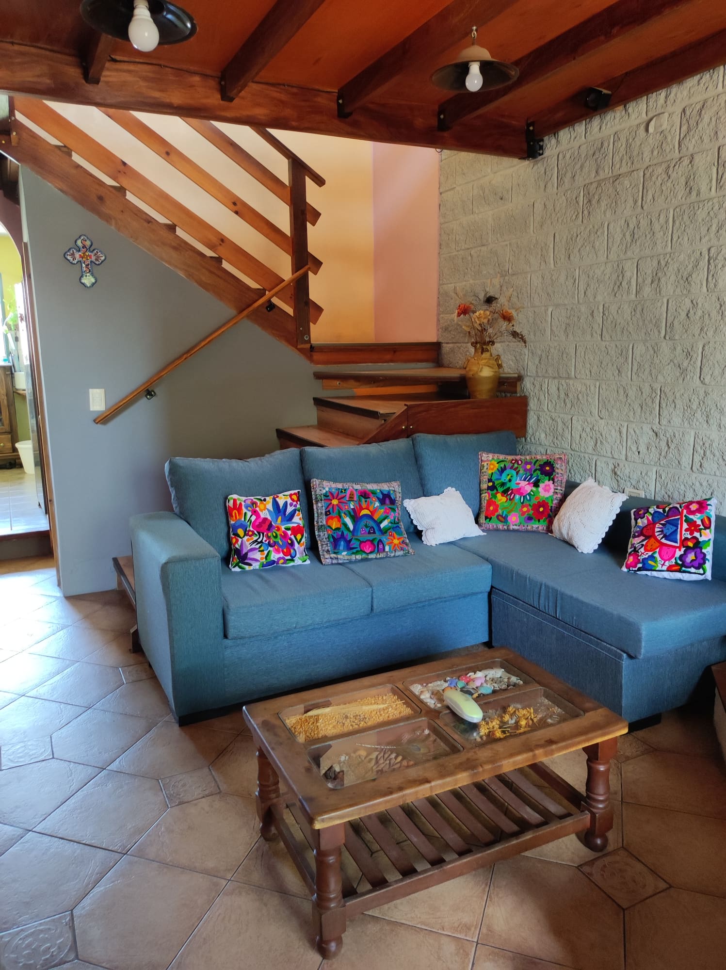 Living con sillón gris, mesa ratona de madera y lámpara colgante
